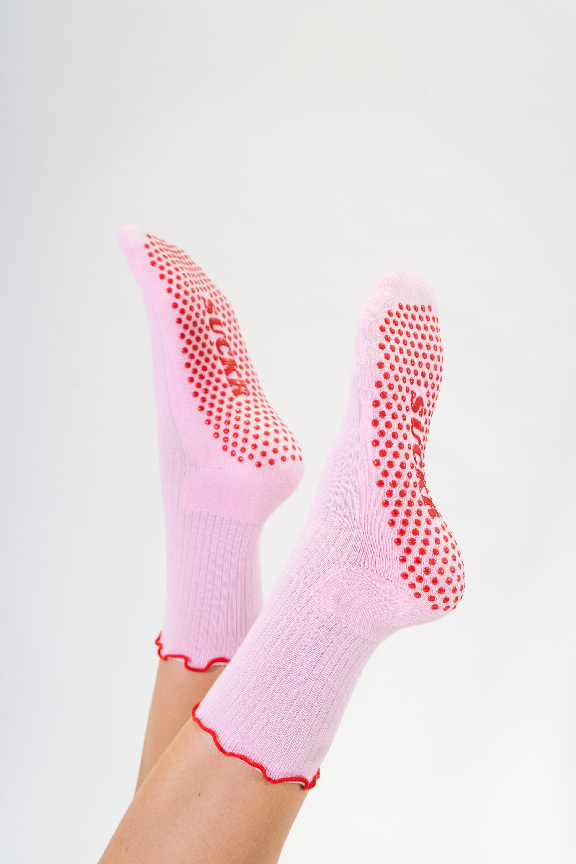 SUCKR Pink frill grip socks, feet in the air
